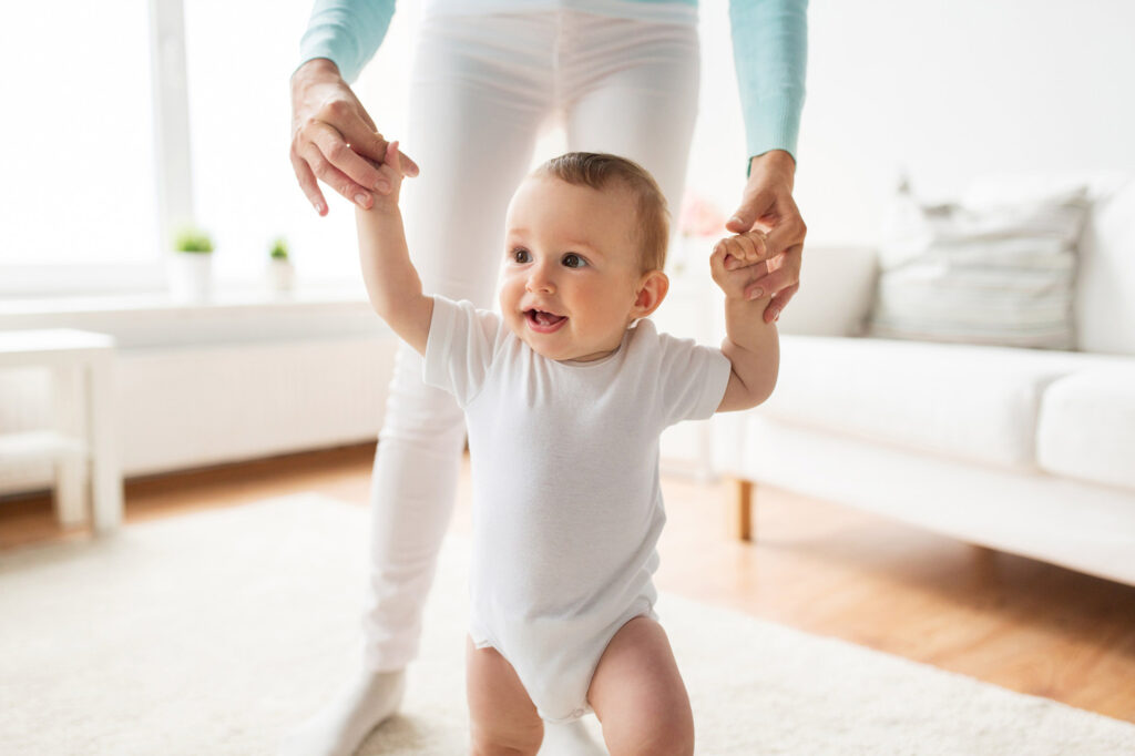 Bébé apprenant à marcher avec l'aide de sa maman.